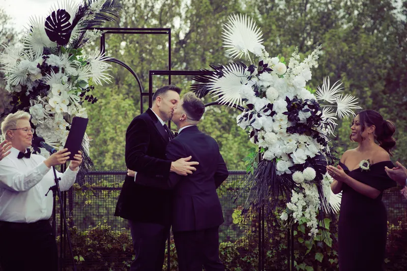 Two grooms share a kiss at the end of their ceremony