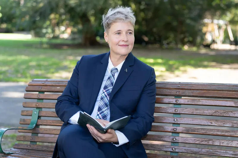 Lizanne sitting on a park bench holding a notebook