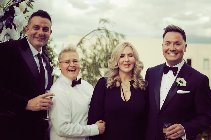 Lizanne with a couple and a guest, all smiling with drinks after the ceremony